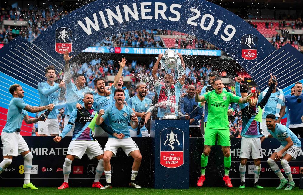 Manchester City's Belgian captain Vincent Kompany (C) lifts the winner's trophy as the players celebrate victory after the English FA Cup final football match between Manchester City and Watford at Wembley Stadium in London, on May 18, 2019. — AFP