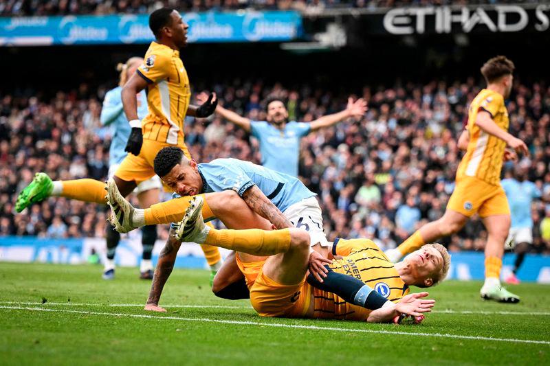 Manchester City's Brazilian midfielder #26 Savinho (up) collides with Brighton's Dutch defender #29 Jan Paul van Hecke as he shoots the ball and misses to score during the English Premier League football match between Manchester City and Brighton and Hove Albion at the Etihad Stadium in Manchester, north west England, on March 15, 2025. - AFPPIX