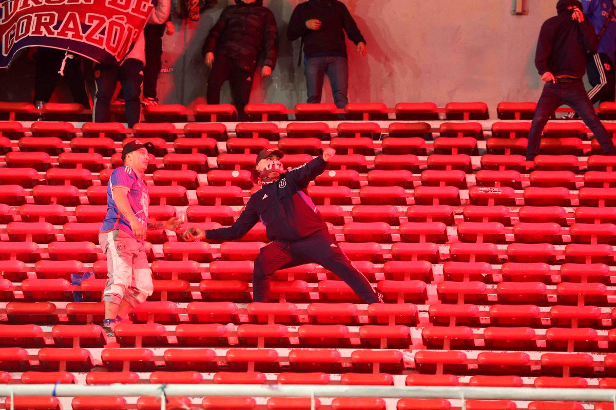 A fan of Universidad de Chile prepares to throw a stone during the interruption of the Copa Sudamericana round of 16 second leg football match between Argentina’s Independiente and Chile’s Universidad de Chile at the Libertadores de America stadium in Avellaneda, Buenos Aires province, Argentina on August 20, 2025. (Photo by Alejandro PAGNI / AFP)