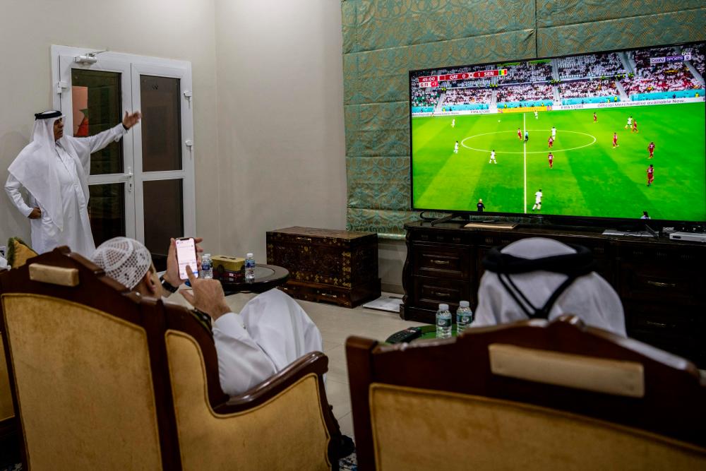 A group of men watch the Qatar 2022 World Cup football tournament match between Qatar and Senegal at Qatari businessman Youssef Al Taher’s home in his farm in the Al Jumayliyah area, northwest of Doha, on November 25, 2022. AFPPIX