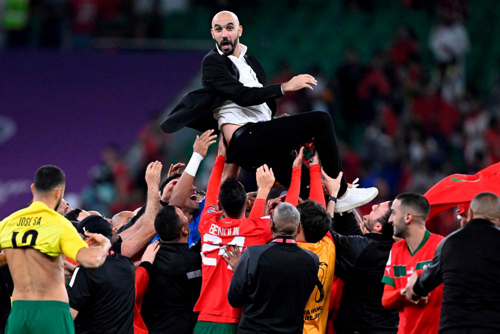 Morocco’s players carry their coach Walid Regragui as they celebrate after winning the Qatar 2022 World Cup quarter-final football match between Morocco and Portugal at the Al-Thumama Stadium in Doha on December 10, 2022. AFPPIX