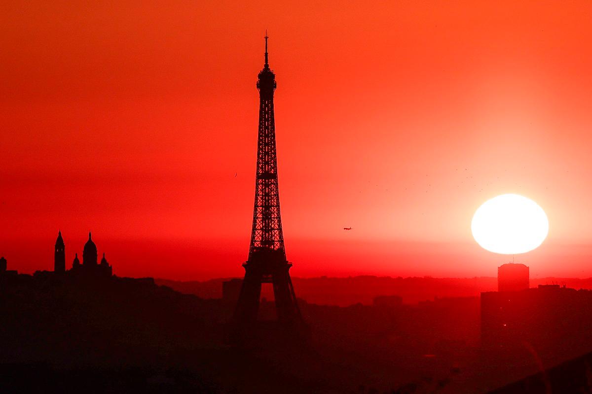 The sun rises by the Eiffel Tower and the Sacre Coeur Basilica ontop of the Montmartre hill in Paris on July 1, 2025, as the city is on red alert for high temperatures, with the top of the Eiffel Tower shut, polluting traffic banned and speed restrictions in place as a searing heatwave gripped Europe. - AFPpix