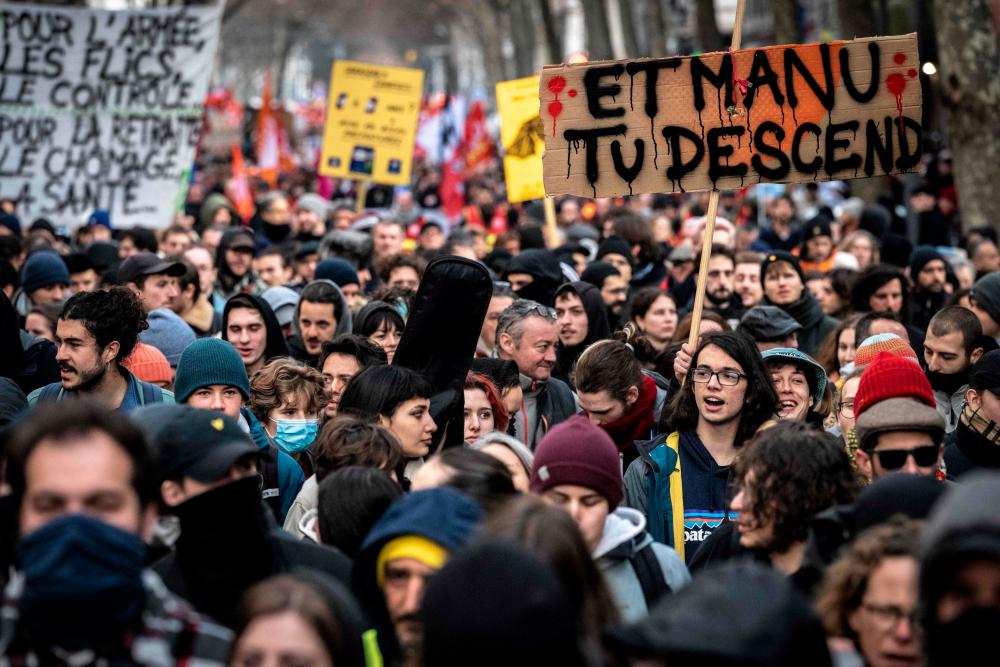 A protester holds a placard reading “Manu (French President Emmanuel Macron) get down here !” during a demonstration as part of a nationwide day of strikes and rallies for the second time in a month, to protest a planned reform to boost the age of retirement from 62 to 64, in Lyon, central eastern France, on January 31, 2023. AFPPIX