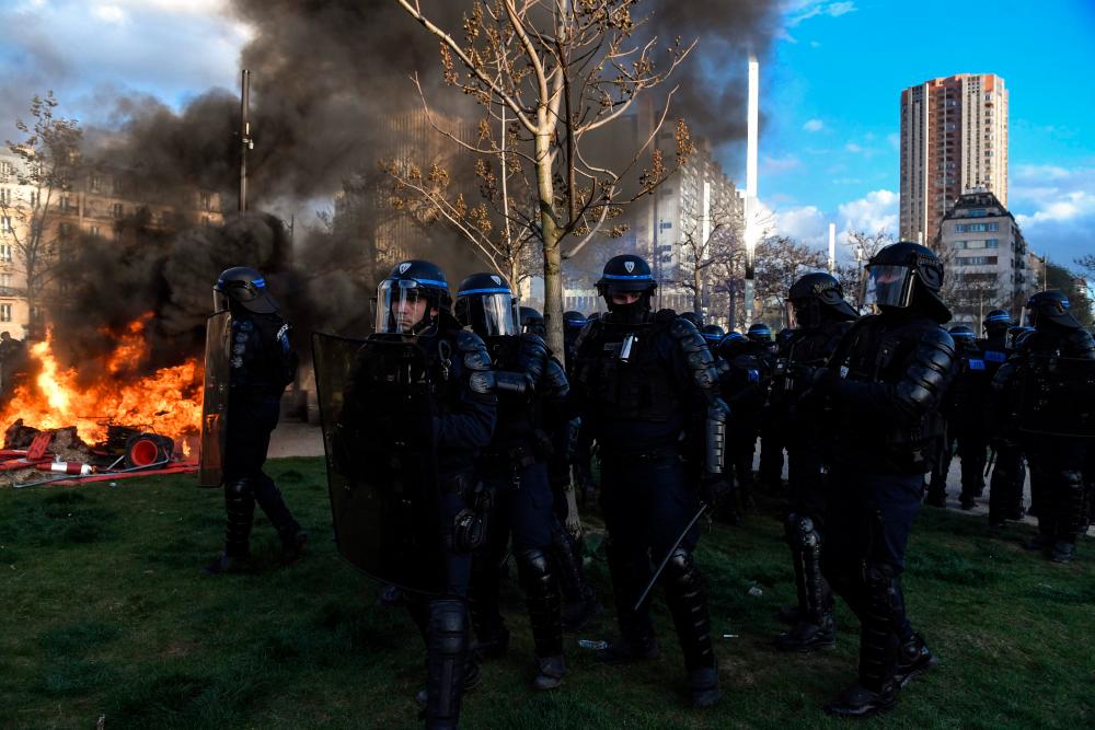 French riot police officers walk past as fire during a demonstration at Place d’Italie on the 11th day of action after the government pushed a pensions reform through parliament without a vote, using the article 49.3 of the constitution, in Paris on April 6, 2023. AFPPIX