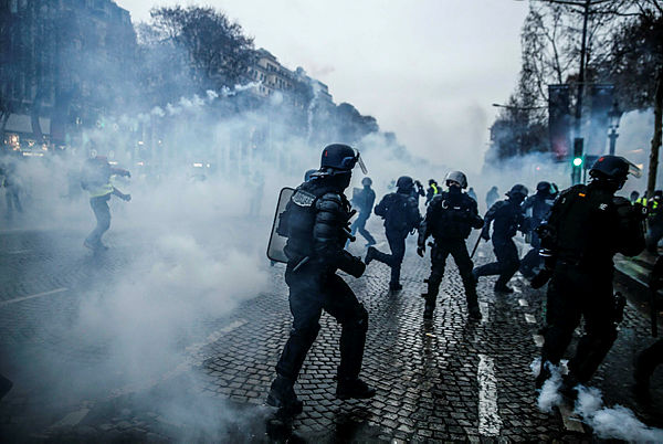 French riot police stand amid smoke of tear gas during clashes with protesters during a demonstration of yellow vests (gilets jaunes) against rising costs of living they blame on high taxes on the Champs-Elysees avenue in Paris, on Dec 15, 2018. — AFP