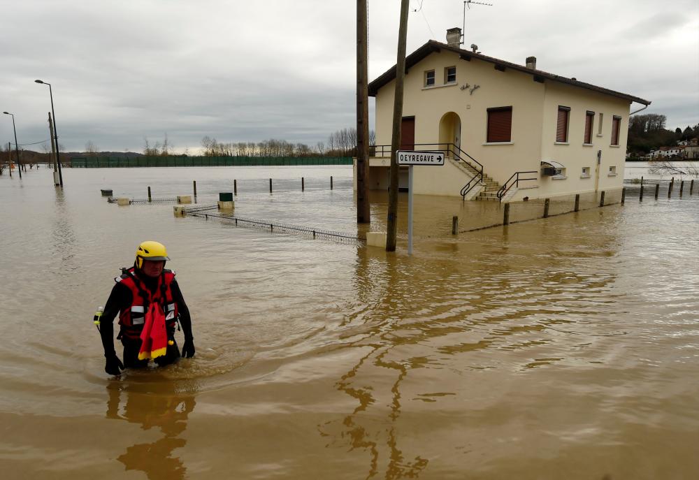 A firefighter walks in a flooded neighbourhood following heavy rains in Peyrehorade, southwestern France, on Dec 14. — AFP