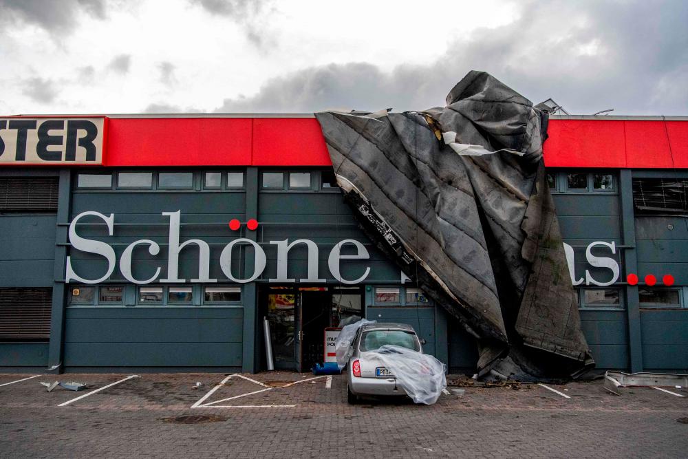 Parts of a roof hang over the facade of an interior decoration store in Paderborn, western Germany on May 20, 2022, after a storm caused major damage. AFPPIX