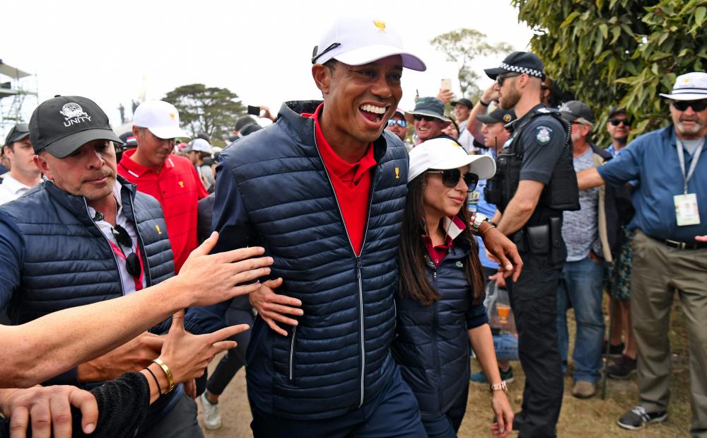 US team captain Tiger Woods (C) celebrates with girlfriend Erica Herman after the US won the Presidents Cup golf tournament on the final day in Melbourne on Dec 15. — AFP