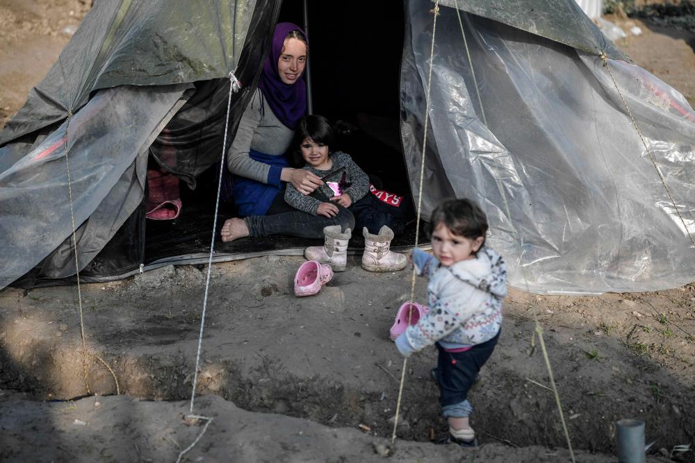 A syrian woman sits in her tent with her children in the Vial refugee camp, on the Greek island of Chios, on Dec 10. — AFP