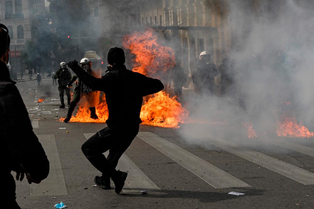 Protesters throw stones and molotov towards riot police in the center of the capital, as clashes broke-out during a 24-hour strike in Athens on March 16, 2023. AFPPIX
