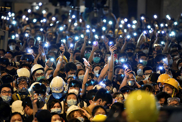 Protesters hold up their mobile phones as they gather outside the police headquarters in Hong Kong on June 21, 2019. - AFP