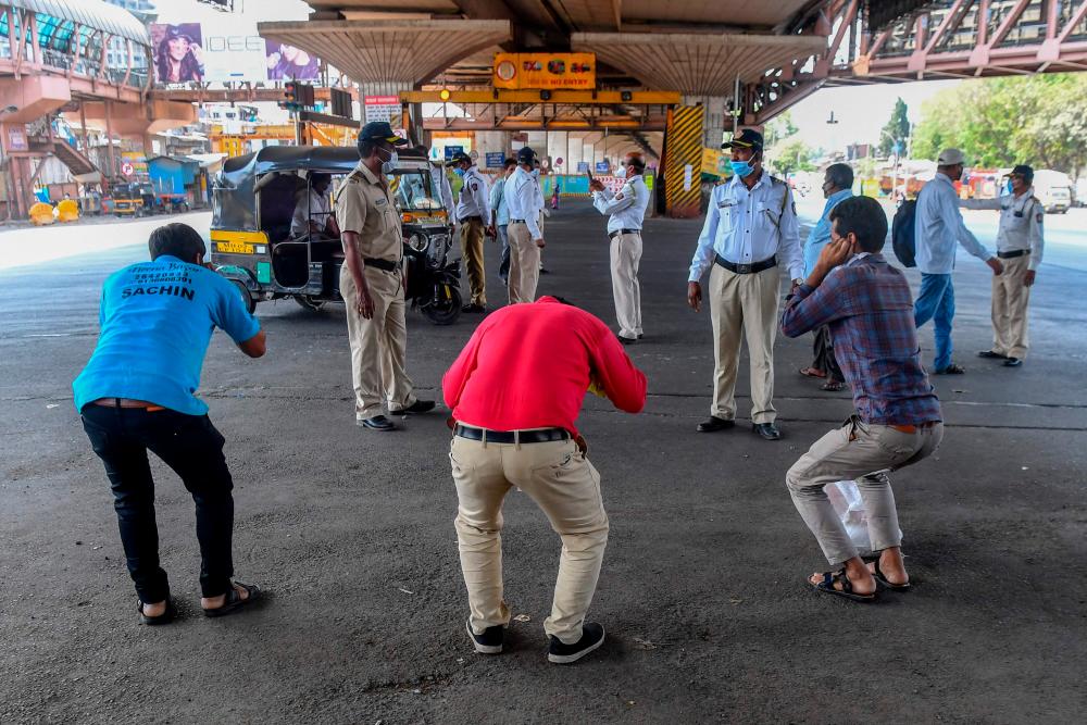 Policemen (background) ask people to do sit-ups as punishment for going out without a valid reason during a government-imposed nationwide lockdown as a preventive measure against the COVID-19 coronavirus, in Mumbai on March 31, 2020. — AFP