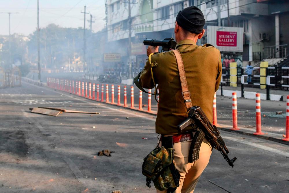 A security personnel fires tear gas during a curfew in Guwahati on Dec 12, following protests over the government's Citizenship Amendment Bill (CAB). — AFP