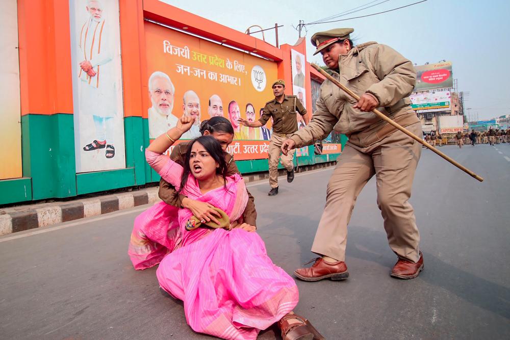A Samajwadi Party activist (C in pink) is being held by police personnel as she protests against the Unnao rape case during a demonstration at Vishan Sabha, the seat of the legislature of Uttar Pradesh state, in Lucknow on Dec 7. — AFP