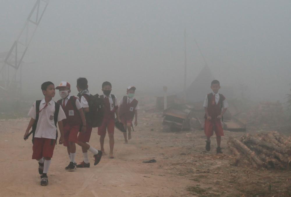 School children make their way to school as haze from forest fires blankets Palembang on Oct 14, 2019. — AFP