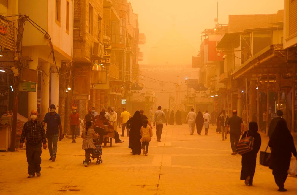 People walk down al-Rasoul street leading to the Imam Ali shrine during a sandstorm in Iraq’s holy city of Najaf on May 16, 2022. AFPPIX
