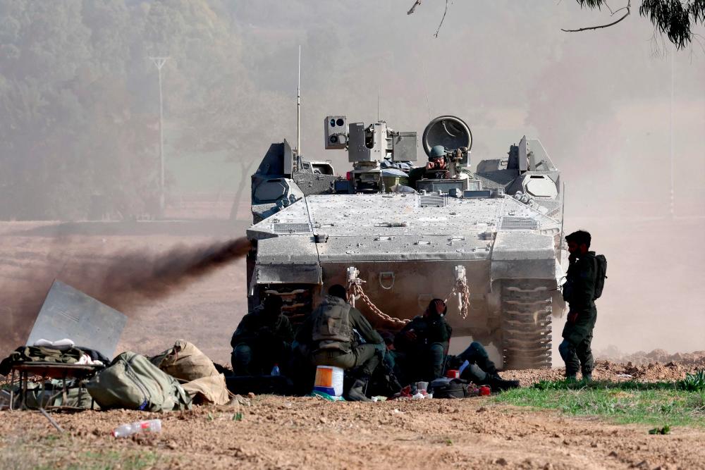 TOPSHOT - A picture taken from a position in southern Israel along the border with the Gaza Strip on December 29, 2023, shows an Israeli army APC (Armored Personal Carrier) rolling on, amid continuing battles between Israel and the militant group Hamas. - AFPPIX