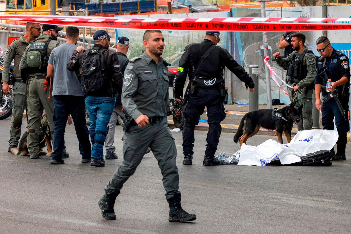 Israeli security forces gather by a body next to a bus at the Ramot road junction in Israeli-annexed east Jerusalem on September 8, 2025. (Photo by Menahem Kahana / AFP)