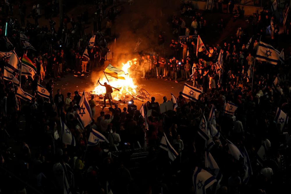 Protesters block a road and hold national flags as they gather around a bonfire during a rally against the Israeli government’s judicial reform in Tel Aviv, Israel on March 27, 2023. AFPPIX
