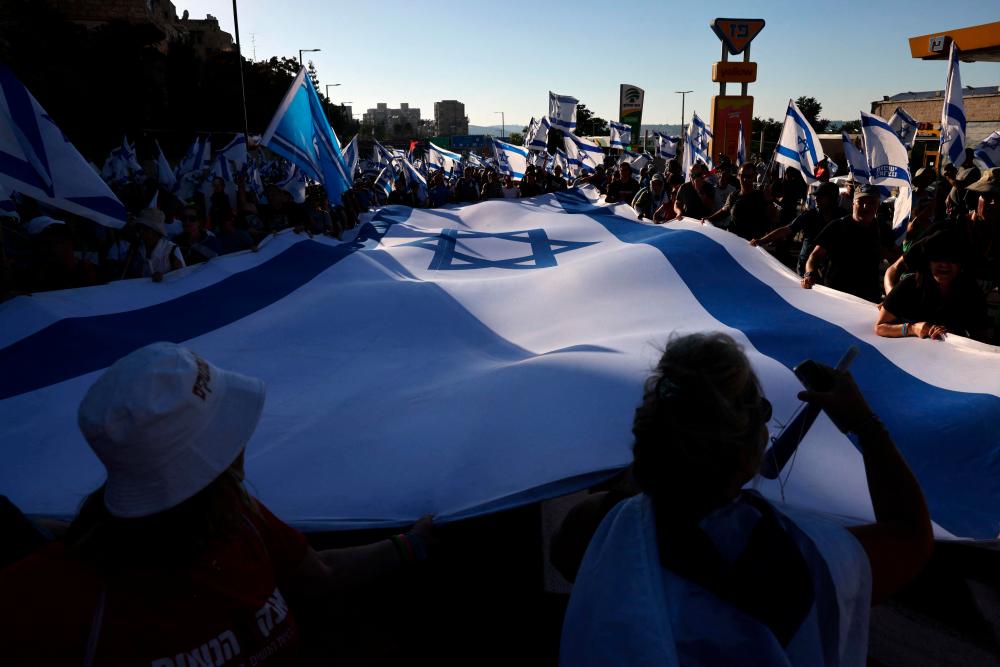 Demonstrators wave an Israeli flag as they march into Jerusalem on July 22, 2023, during a multi-day march that started in Tel Aviv to protest the government’s judicial overhaul bill ahead of a vote in the parliament. AFPPIX