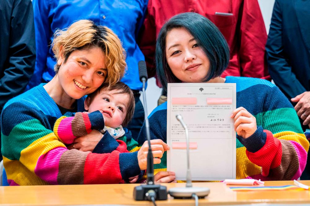Mamiko Moda (L) and her partner Satoko Nagamura with their son holds a same-sex partnership certificate as they pose for a photograph after a press conference at the Tokyo Metropolitan Government building in Tokyo on November 1, 2022. AFPPIX