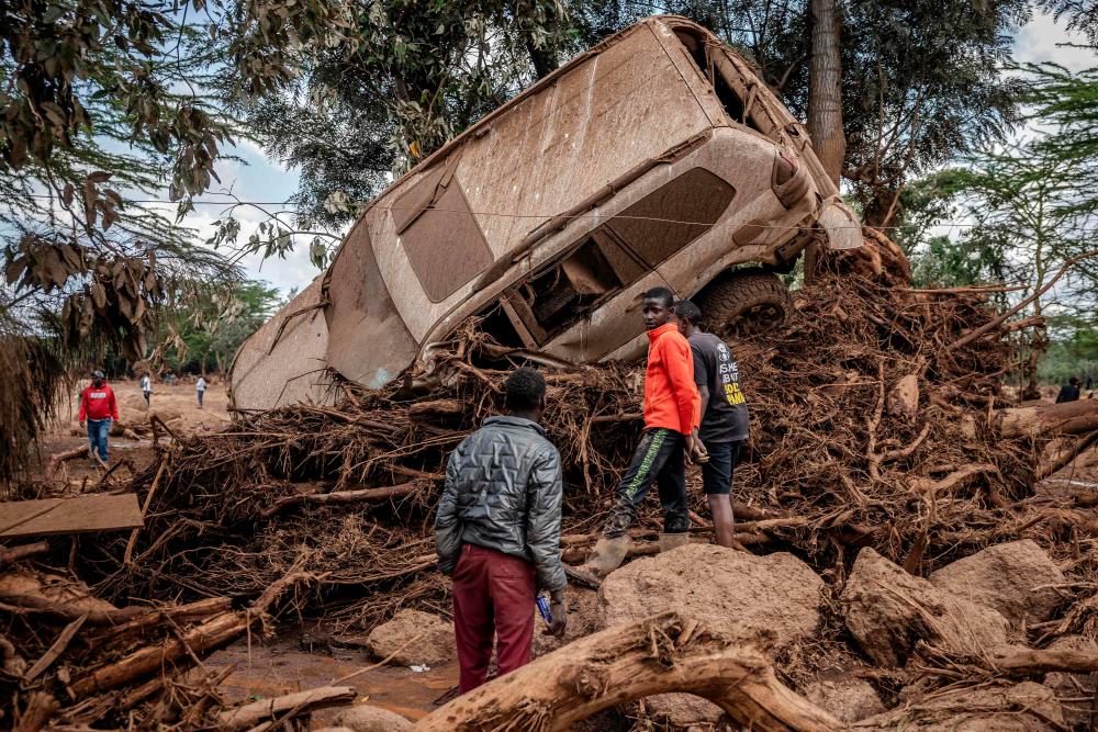 Young men inspect a destroyed car carried by waters in an area heavily affected by torrential rains and flash floods in the village of Kamuchiri, near Mai Mahiu, on April 29, 2024. At least 45 people died when a dam burst its banks near a town in Kenya’s Rift Valley, police said on April 29, 2024, as torrential rains and floods battered the country/AFFPix