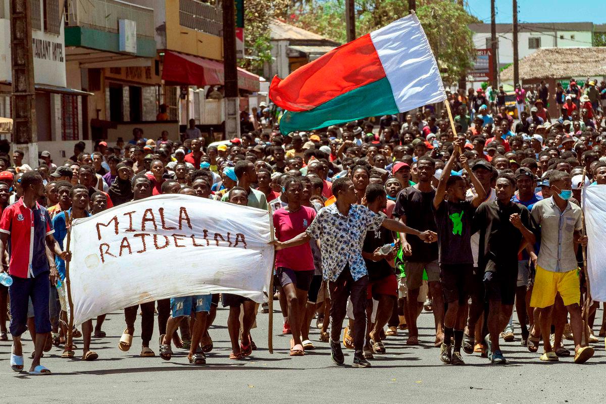 Protesters carry a Madagascar flag and a banner during an anti-government protest in Antsiranana on October 1, 2025. (Photo by FITA / AFP)