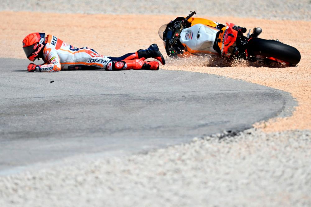 Honda Spanish rider Marc Marquez falls after crashing with Aprilia Portuguese rider Miguel Oliveira (out of frame) during the MotoGP race of the Portuguese Grand Prix at the Algarve International Circuit in Portimao, on March 26, 2023. AFPPIX