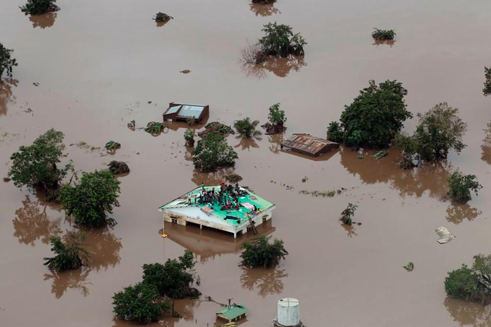 This handout picture taken and released on March 18, 2019, by the Mission Aviation Fellowship shows people on a roof surrounded by flooding in an area affected by Cyclone Idai in Beira. — AFP