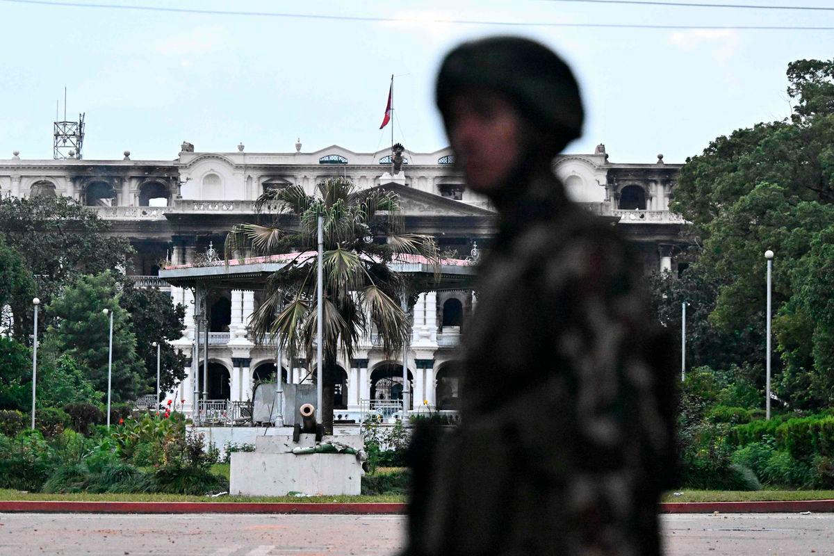 Army personnel stands guard near Singha Durbar, the main administrative building for the Nepal government, after it was set ablaze by protesters, in Kathmandu on September 12, 2025. The army has imposed a curfew in the Himalayan nation of 30 million people, with soldiers patrolling the largely quiet streets after the worst violence in two decades. (Photo by Pedro Pardo / AFP)