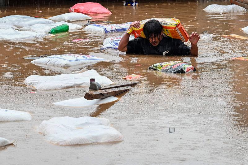 A man carrying a sack of flour wades through flood waters after the Bagmati River overflowed following heavy monsoon rains in Kathmandu - AFPpix