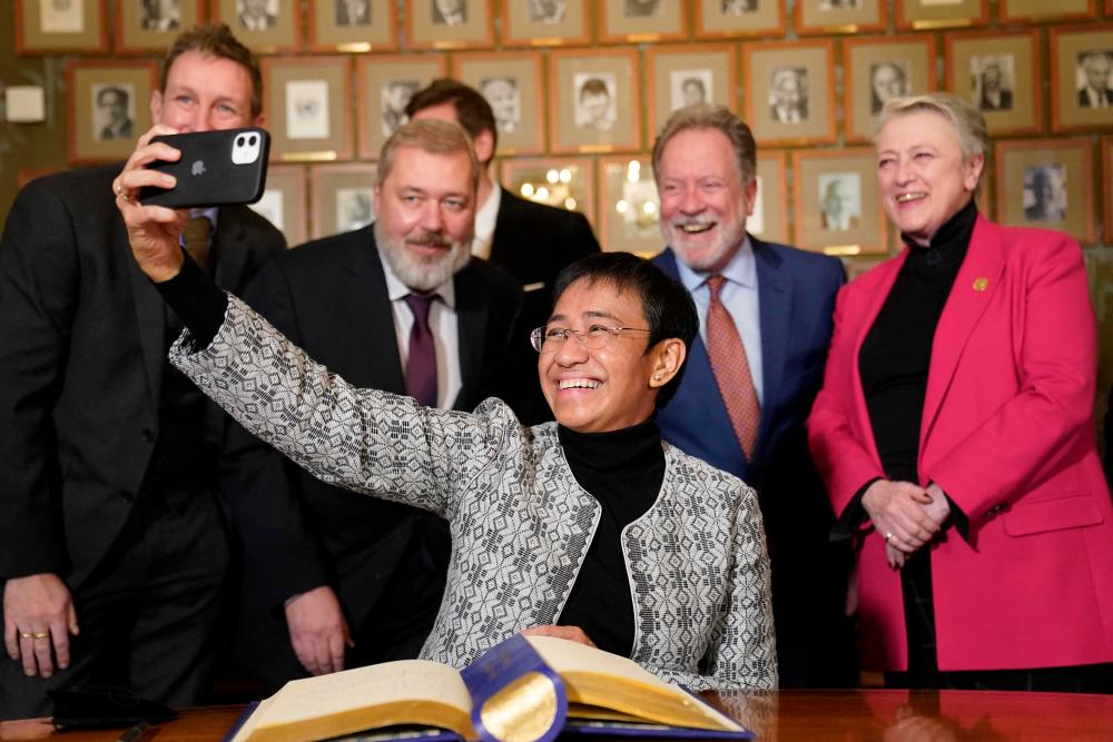 TOPSHOT - Nobel Peace Prize winner Maria Ressa takes a selfie with the Nobel Committee and co-prize winner Dimitrij Muratov after a press conference at the Norwegian Nobel Institute in Oslo on December 9, 2021, the day before the awarding ceremony of the Nobel Peace Prize. AFPpix