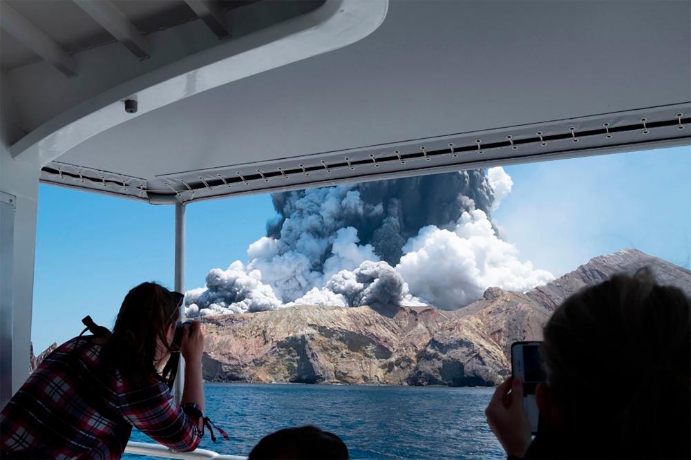 This handout photograph courtesy of Michael Schade shows the volcano on New Zealand's White Island spewing steam and ash moments after it erupted on Dec 9. — AFP