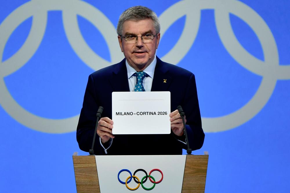 International Olympic Committee (IOC) president Thomas Bach shows the card with the name Milan/Cortina d’Ampezzo as the winning name of the 2026 Winter Olympics during the 134th session of the International Olympic Committee (IOC), in Lausanne on June 24, 2019. — AFP
