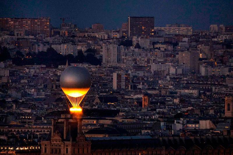 The Olympic cauldron is lit with the Olympic flame as it flies above Paris while attached to a balloon as seen from the Eiffel Tower - AFPpix