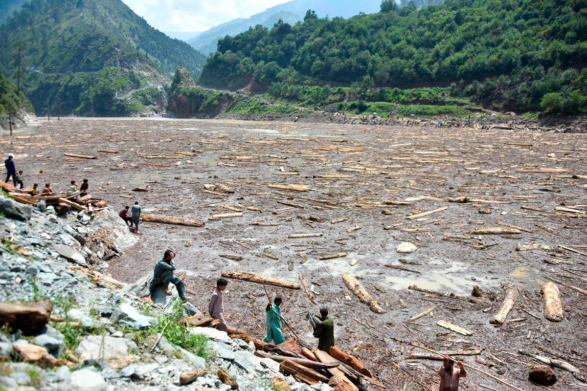 Locals collect woods from Noseri Dam near Muzaffarabad, the capital of Pakistan-administered Kashmir, on August 16, 2025, a day after flash floods. Rescuers were struggling to retrieve bodies from debris after flash floods triggered by heavy monsoon rains across northern Pakistan killed at least 344 people in the past 48 hours, authorities said on August 16. Photo by Sajjad QAYYUM / AFP