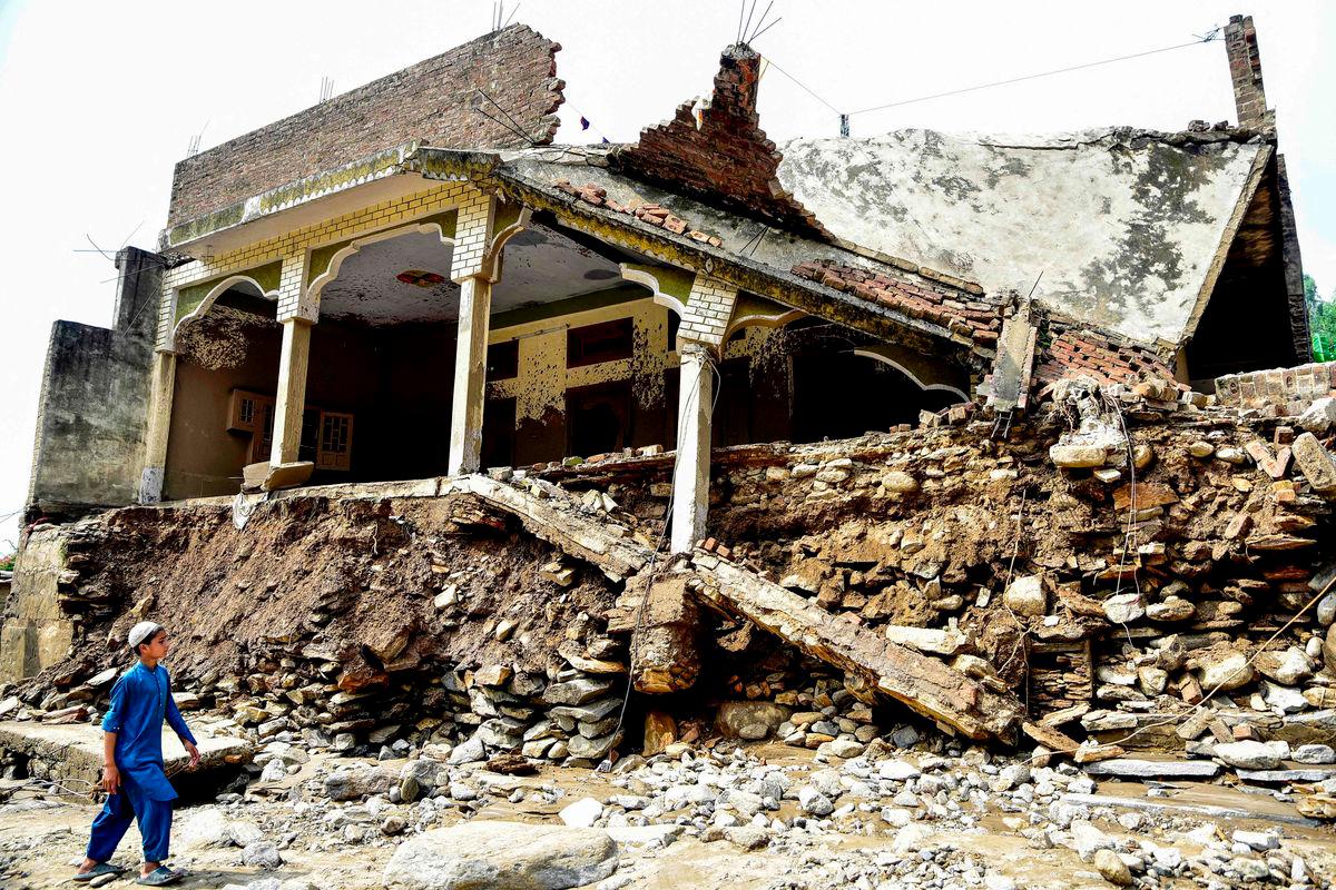 A boy walks past a damaged house a day after flash floods in the Buner district of the monsoon-hit northern Pakistan’s mountainous Khyber Pakhtunkhwa province on August 16, 2025. Rescuers were struggling to retrieve bodies from debris after flash floods triggered by heavy monsoon rains across northern Pakistan killed at least 321 people in the past 48 hours, authorities said on August 16. Photo by Hasham AHMED / AFP