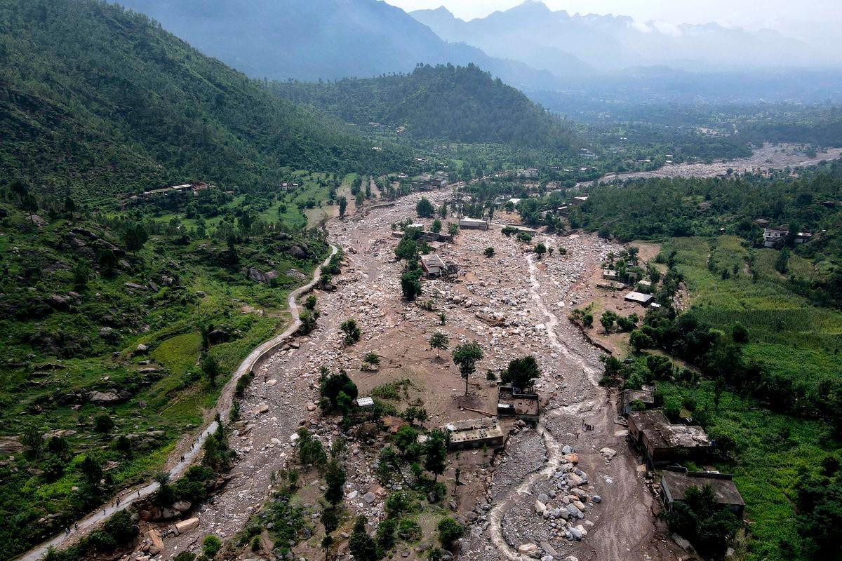 An aerial view shows houses partially submerged in sludge along a riverbed in the aftermath of flash floods at the Buner district of mountainous Khyber Pakhtunkhwa province on August 17, 2025. Pakistani rescuers dug homes out from under massive boulders on August 17, as they searched for survivors of flash floods that killed at least 344 people, with more than 150 still missing. (Photo by Abdul MAJEED / AFP)