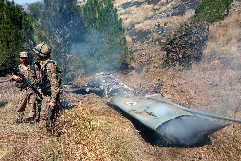 Pakistani soldiers stand next to what Pakistan says is the wreckage of an Indian fighter jet shot down in Pakistan controlled Kashmir at Somani area in Bhimbar district near the Line of Control on Feb 27, 2019. — AFP