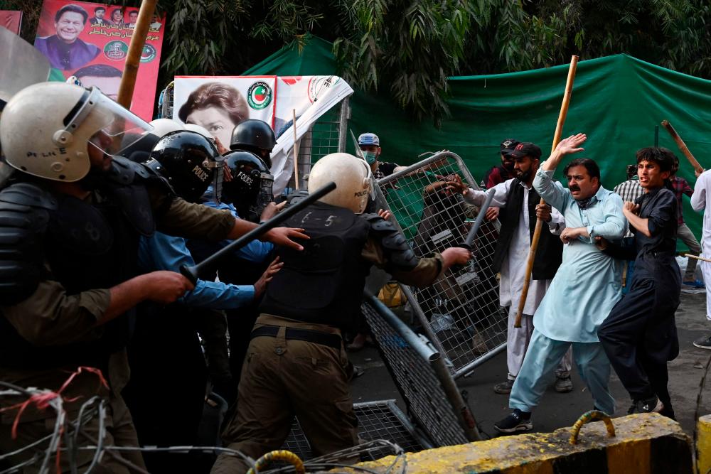 Supporters of former prime minister Imran Khan and riot police scuffle outside Khan’s house to prevent officers from arresting him, in Lahore on March 14, 2023/AFPPix