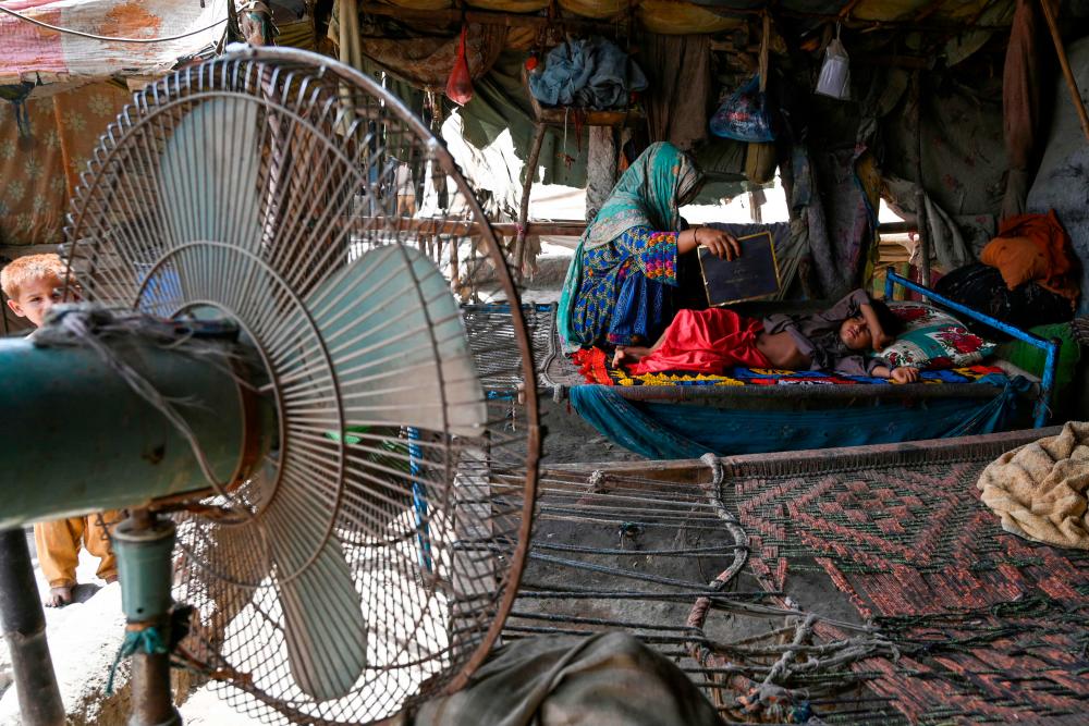 In this picture taken on May 11, 2022, a woman uses a paper sheet to fan her child amid a power cut during a heatwave in Jacobabad, in the southern Sindh province. AFPPIX