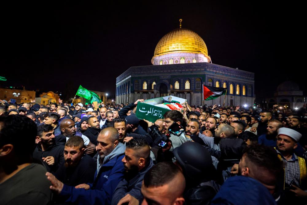 Palestinian mourners carry the body of Walid al-Sharif, 23, who died of wounds suffered last month during clashes with Israeli police at Jerusalem’s flashpoint al-Aqsa mosque compound, on May 16, 2022 in front of the Dome of the Rock mosque at the al-Aqsa compound. AFPPIX