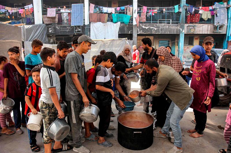 Children queue with pots to receive food aid from a kitchen at the Abu Zeitun school run by the UN Relief and Works Agency for Palestine Refugees (UNRWA) in the Jabalia camp for Palestinian refugees in the northern Gaza Strip on June 13, 2024 amid the ongoing conflict in the Palestinian territory between Israel and Hamas. - AFPpix