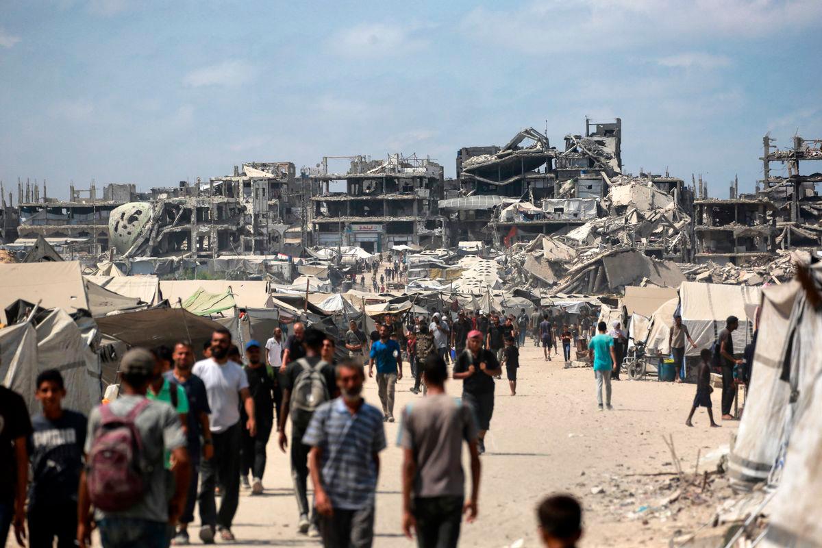 Palestinians walk along a street near war-damaged buildings in Gaza City on August 8, 2025. Israel’s military will “take control” of Gaza City under a plan proposed by Prime Minister Benjamin Netanyahu and approved by his security cabinet, triggered a wave of criticism from across the world. Photo by Bashar TALEB / AFP