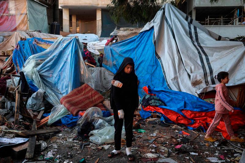 An injured boy stands with other displaced Palestinians amid destroyed tents at a makeshift camp that was hit in Israeli strikes - AFPpix