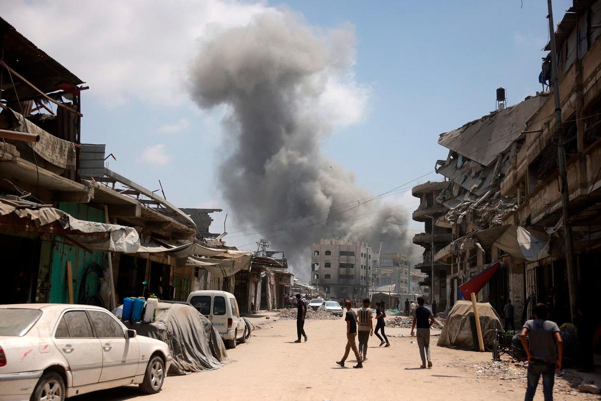 Palestinian watch as a plume of smoke rises during an Israeli strike on Gaza City’s southern al-Zeitoun neighbourhood on August 8, 2025. Israel’s military will “take control” of Gaza City under a new plan approved by Prime Minister Benjamin Netanyahu’s security cabinet, touching off a wave of criticism Friday from both inside and outside the country. - BASHAR TALEB / AFP