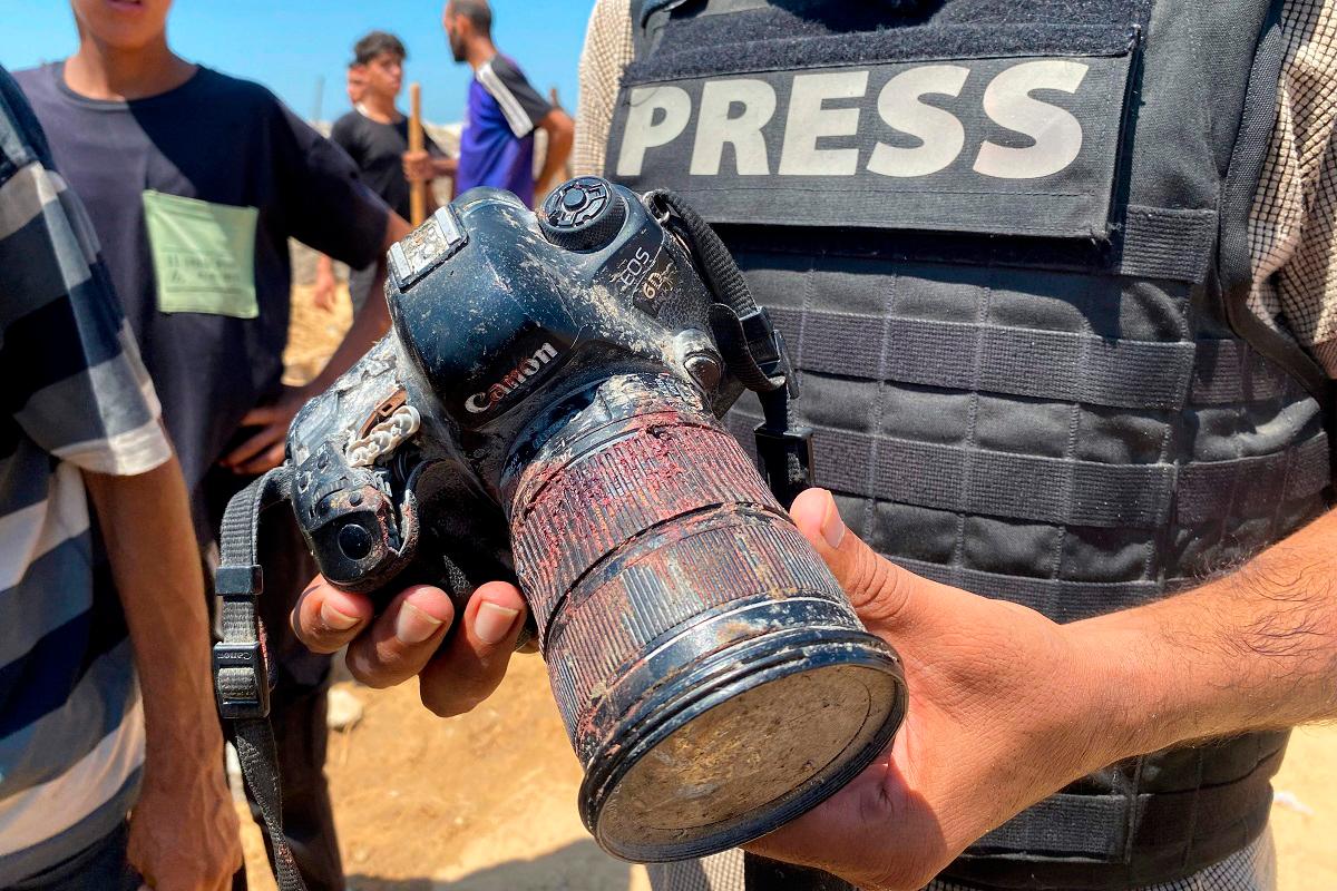 A journalist holds a blood-covered camera belonging to Palestinian photojournalist Hussam al-Masri, a Reuters contractor who was killed in an Israeli strike on Nasser hospital in Khan Yunis in the southern Gaza Strip, during his funeral on August 25, 2025. - AFPpix