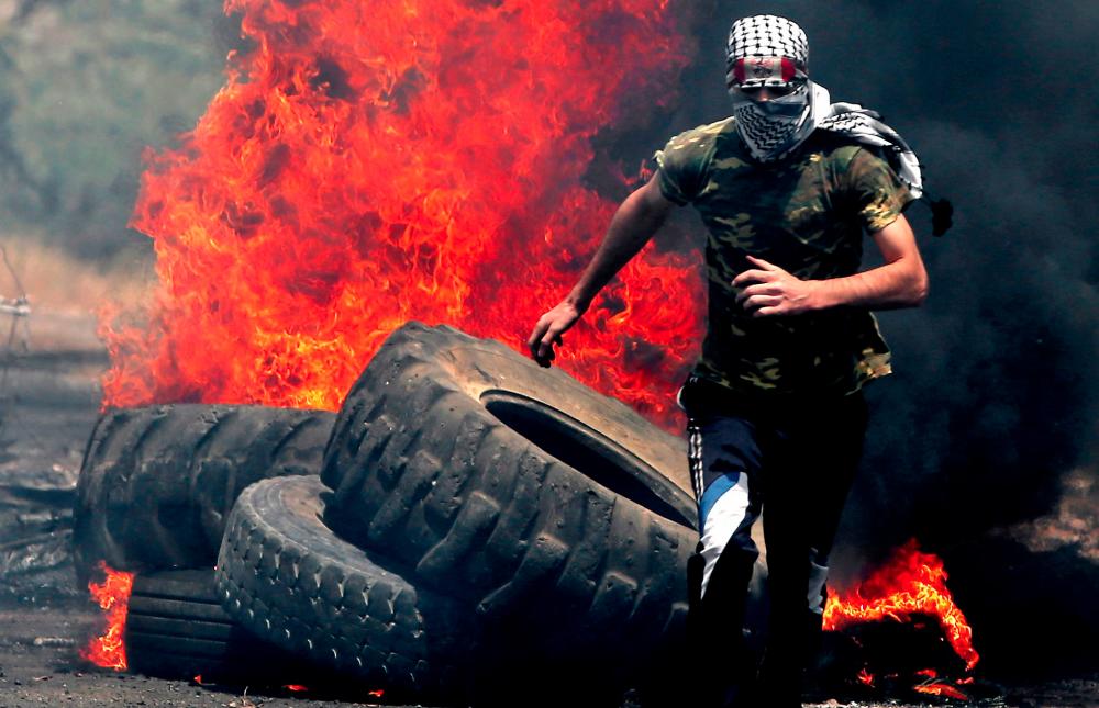 A Palestinian protester runs for cover while being chased by Israeli security forces during a weekly demonstration against the expropriation of Palestinian lands by Israel in the village of Kfar Qaddum, near Nablus in the occupied West Bank on June 7, 2019. — AFP