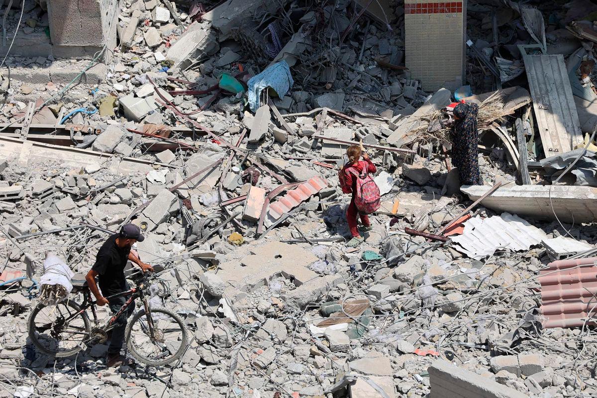Palestinians walk over rubble and debris in the al-Tuffah neighbourhood of Gaza City on August 14, 2025. (Photo by Omar AL-QATTAA / AFP)