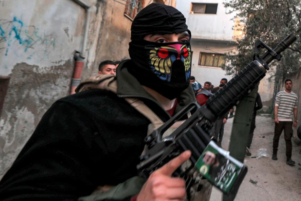 Masked Palestinian gunmen walk along an alley during an Israeli army raid in the Jenin camp for Palestinian refugees in the occupied West Bank on March 7, 2023/AFPPix